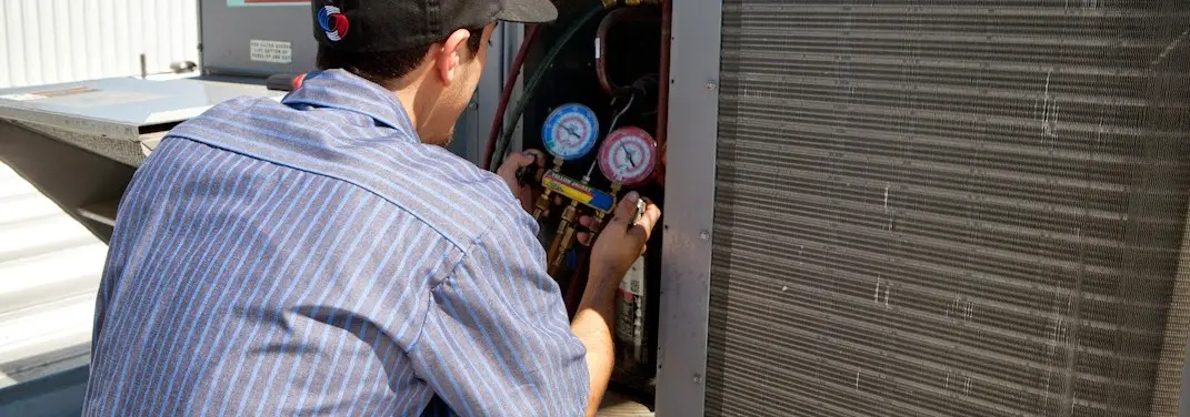 HVAC technician servicing a condenser unit in Pecan Plantation